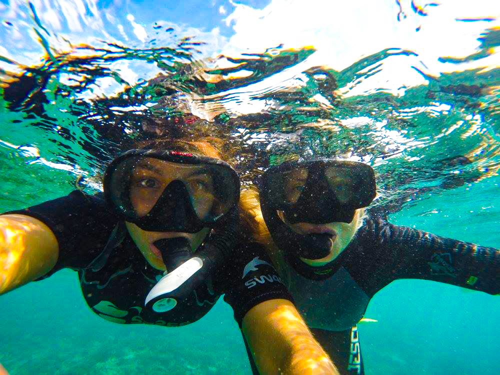 people underwater with googles on staring at the camera
